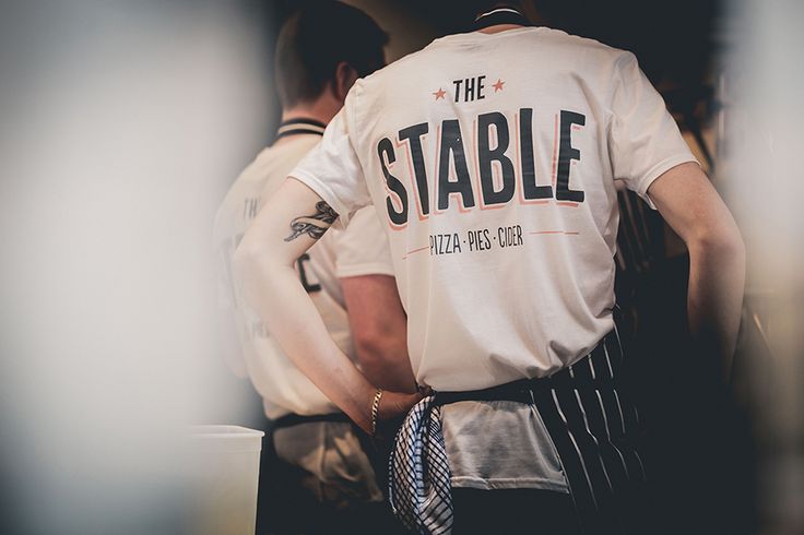 a man wearing a white shirt with the words the stable on it's back