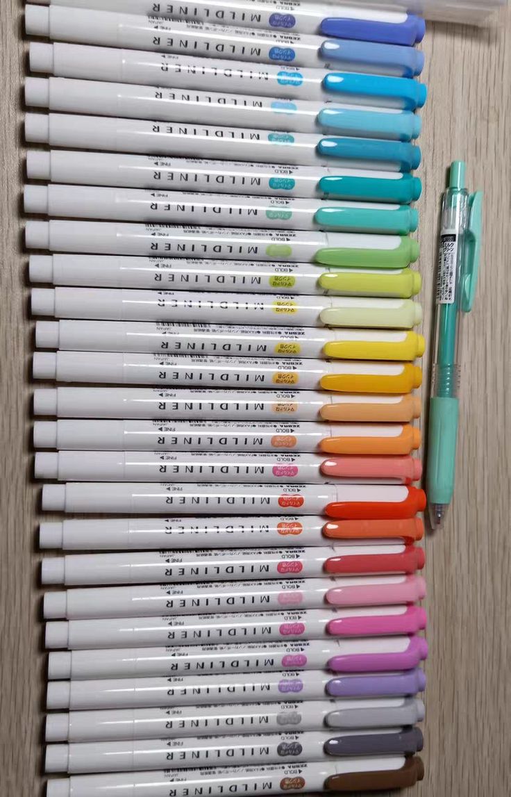 many different colored pens lined up next to each other on a wooden surface with one pen in the middle