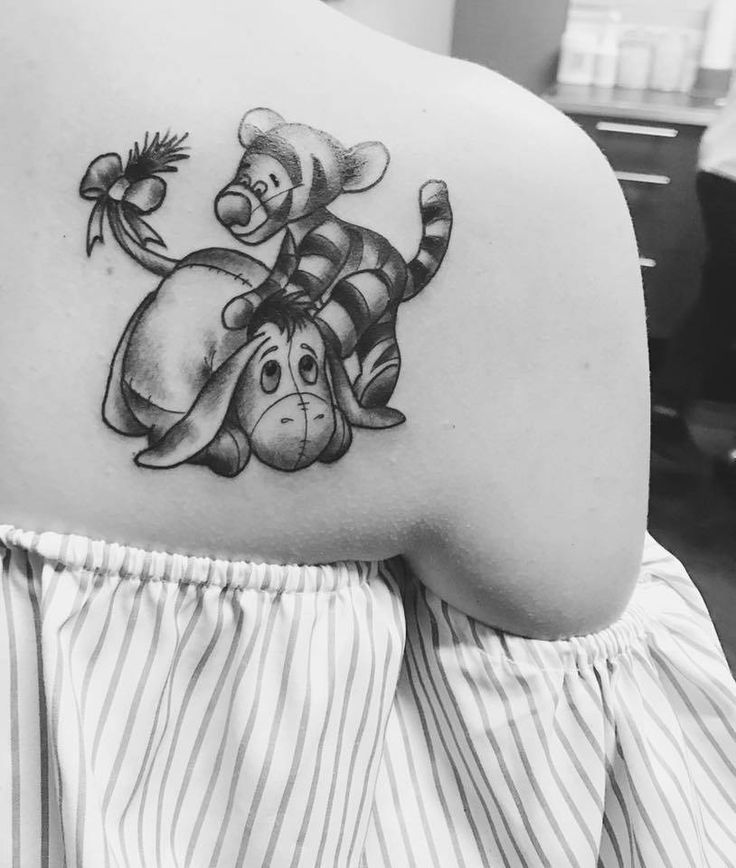 a woman with a tattoo on her shoulder has a winnie the pooh design on it