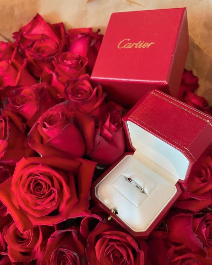 an open ring box sitting on top of red roses