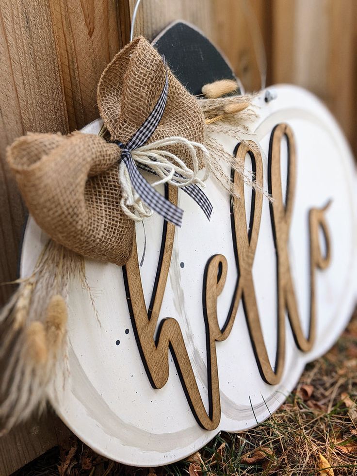 a welcome sign with burlap bow hanging on a wooden fence