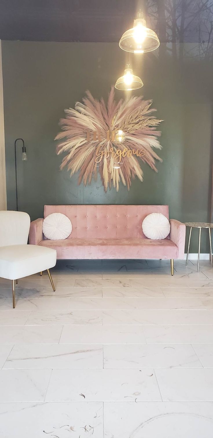 a living room with two chairs and a pink couch in front of a painting on the wall