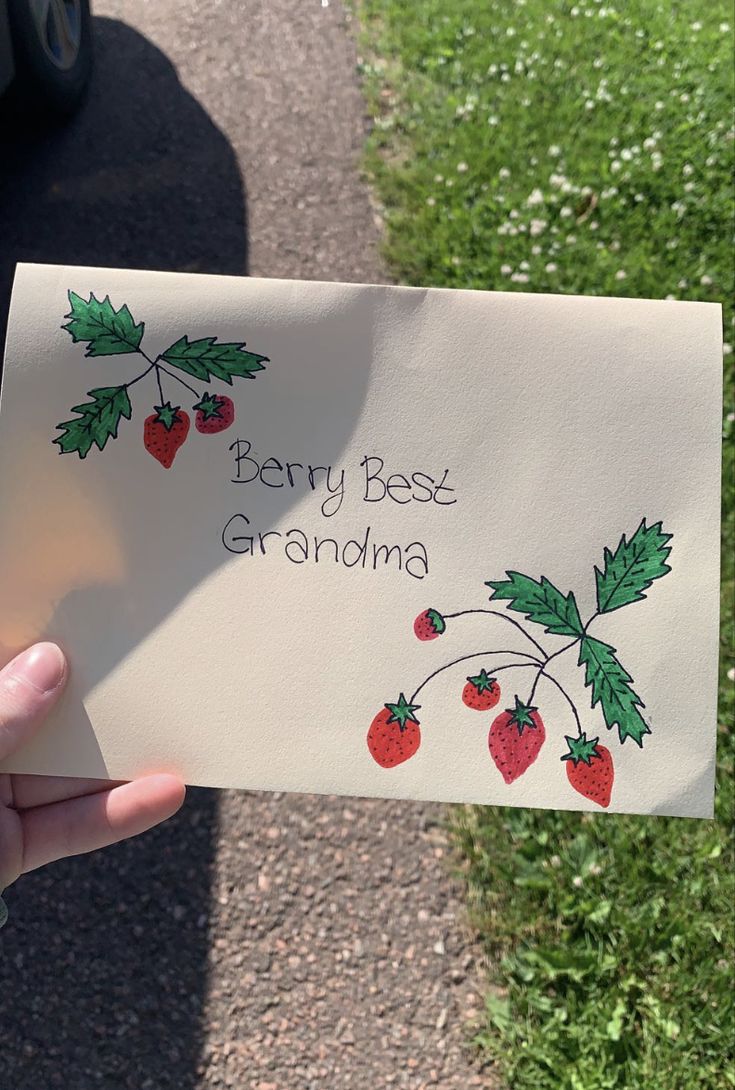 someone holding up a card that says,'berry best grandma'with cherries on it