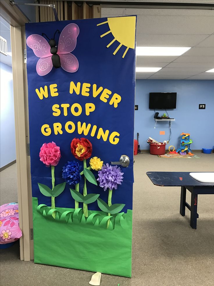 a classroom door decorated with flowers and a sign that says, we never stop growing