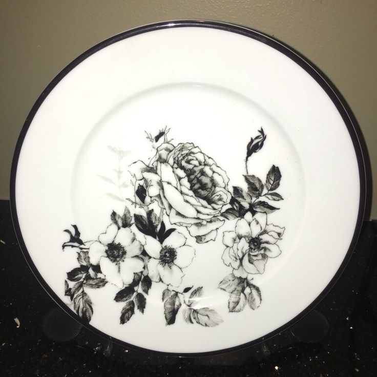 a black and white plate with flowers painted on the side, sitting on a counter