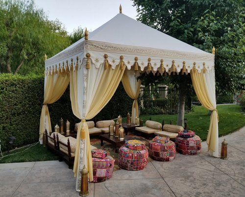 a white tent sitting on top of a patio next to a lush green park filled with lots of trees