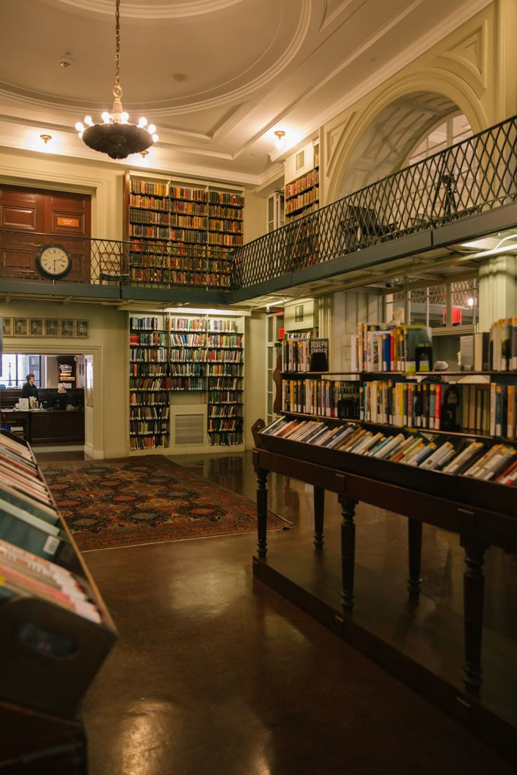 the inside of a library with many books on shelves and a piano in the foreground