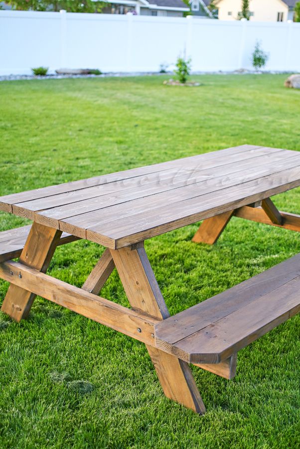 a wooden picnic table sitting on top of a lush green field