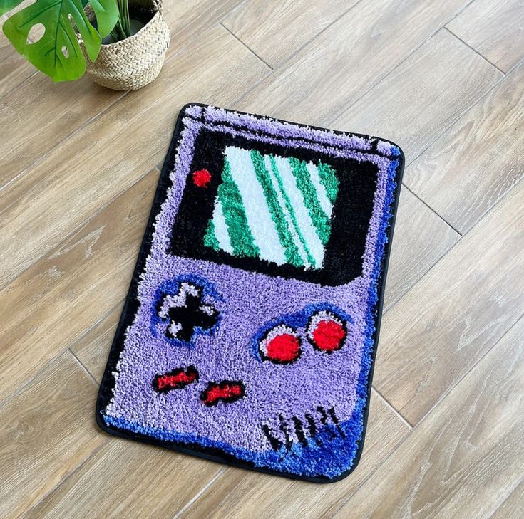 a rug with a gameboy design on the floor next to a potted plant