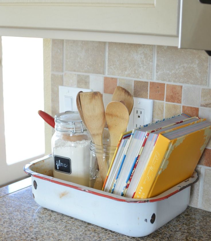 a kitchen counter with books and utensils in a white container on the counter