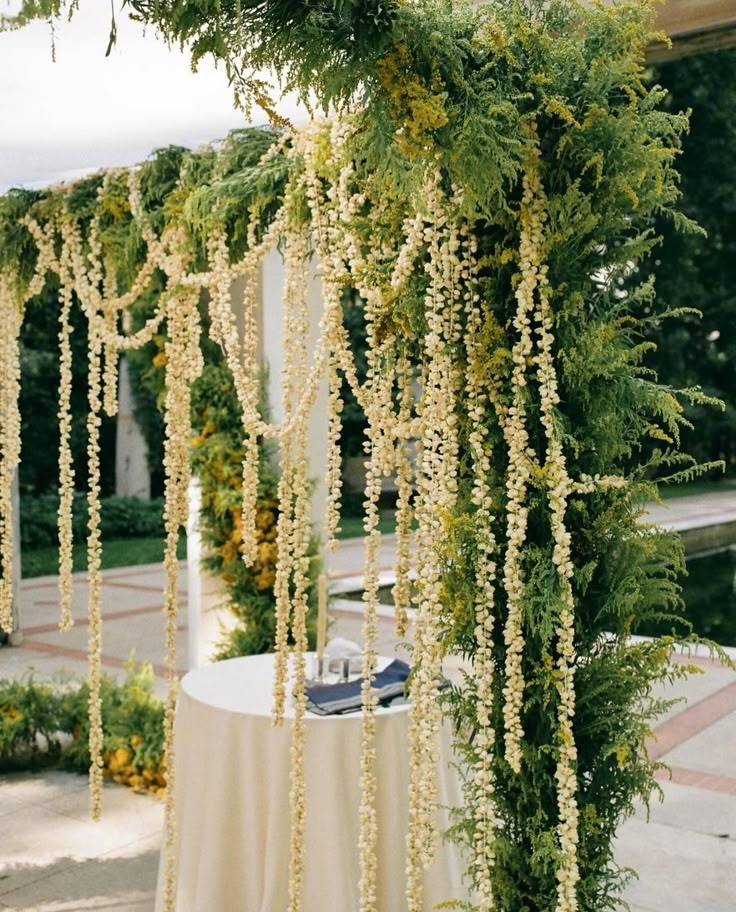 the table is covered with white flowers and greenery for an outdoor wedding ceremony or reception