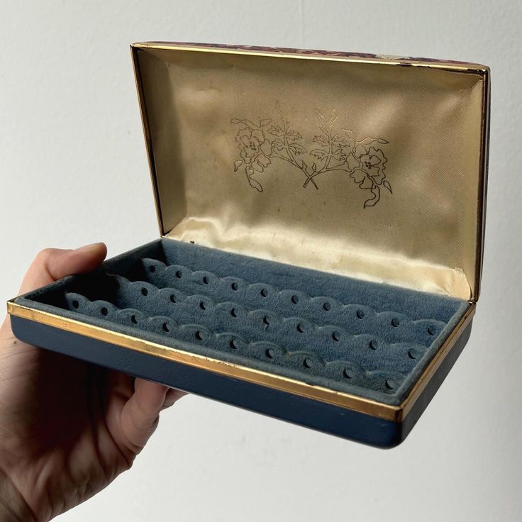 a hand holding an open blue box with drawings on it