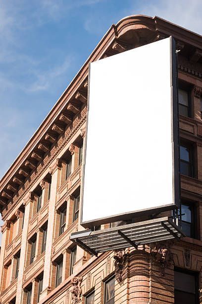 a large white sign hanging from the side of a tall building on a city street