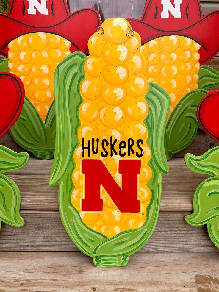 a corn on the cob sign that says huskers n with red and green leaves