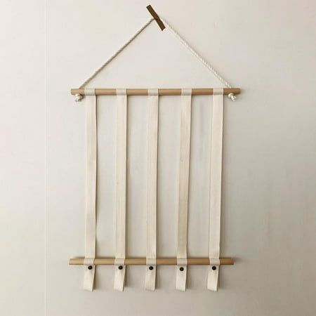 a white wall hanging with four wooden pegs