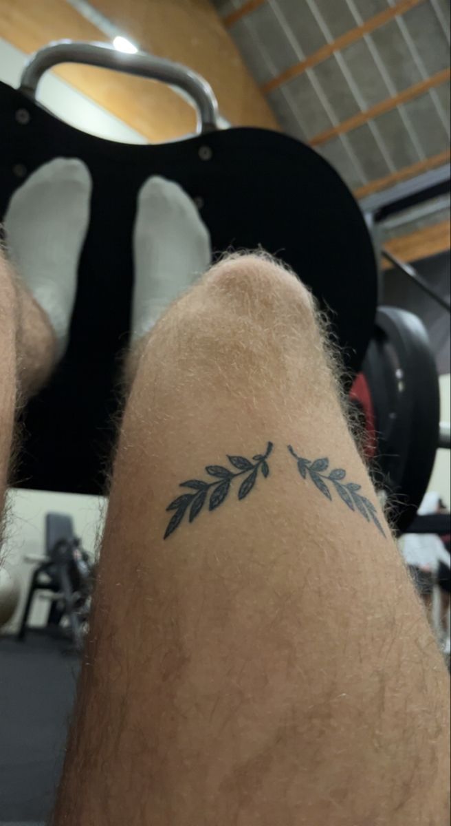 a man's leg with a tattoo on his left side and leaves on the other side