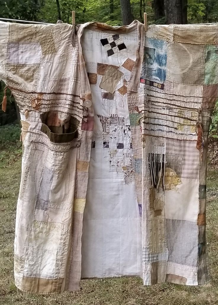 an old dress is hanging on a clothesline in the grass with trees behind it