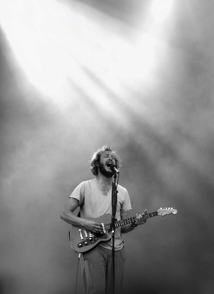 a man standing in front of a microphone while holding a guitar