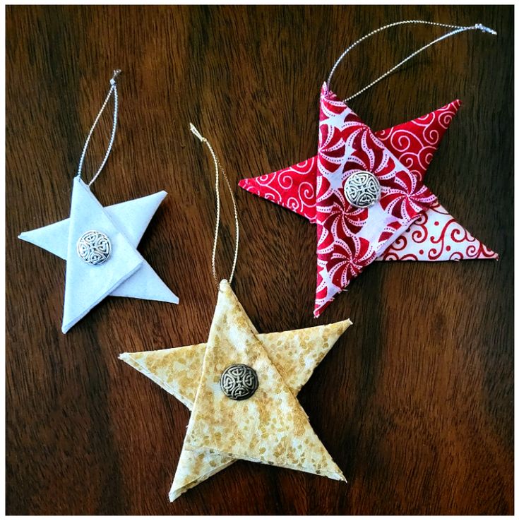 three star ornaments are hanging on a table