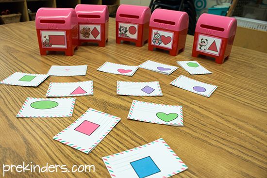 several pieces of paper cut out to spell shapes on a wooden table with pink and green stampers