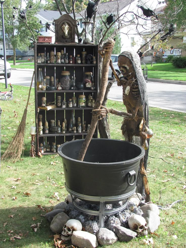 a halloween display in the yard with an old cauldster