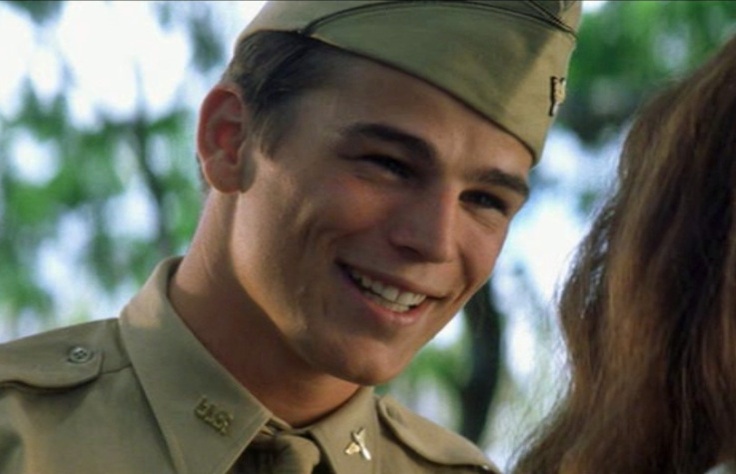 a man in uniform smiles at the camera while standing next to a woman with long hair