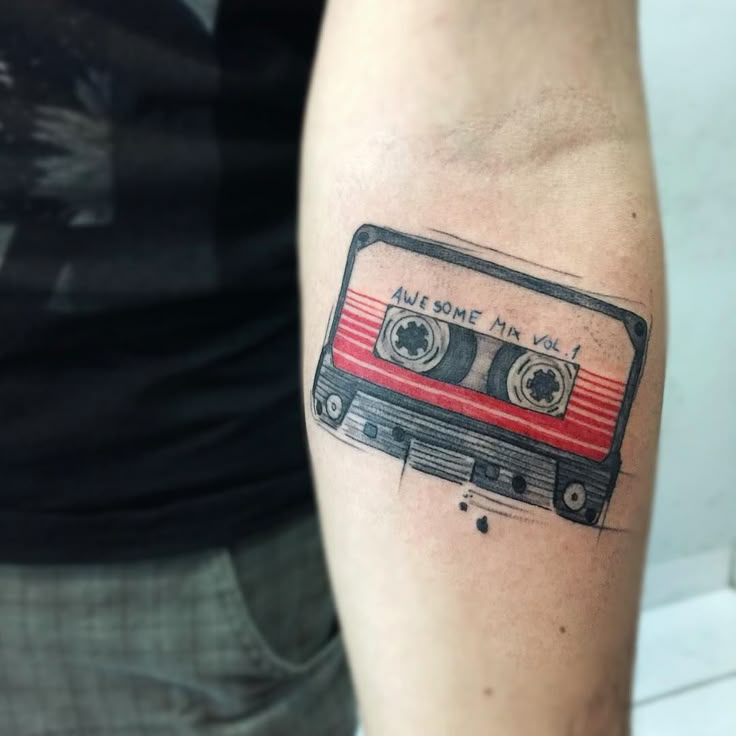 a man with a tattoo on his arm has a red and black cassette tape