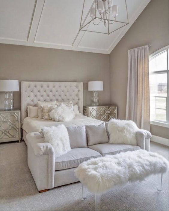 a large white bed sitting in a bedroom next to a window