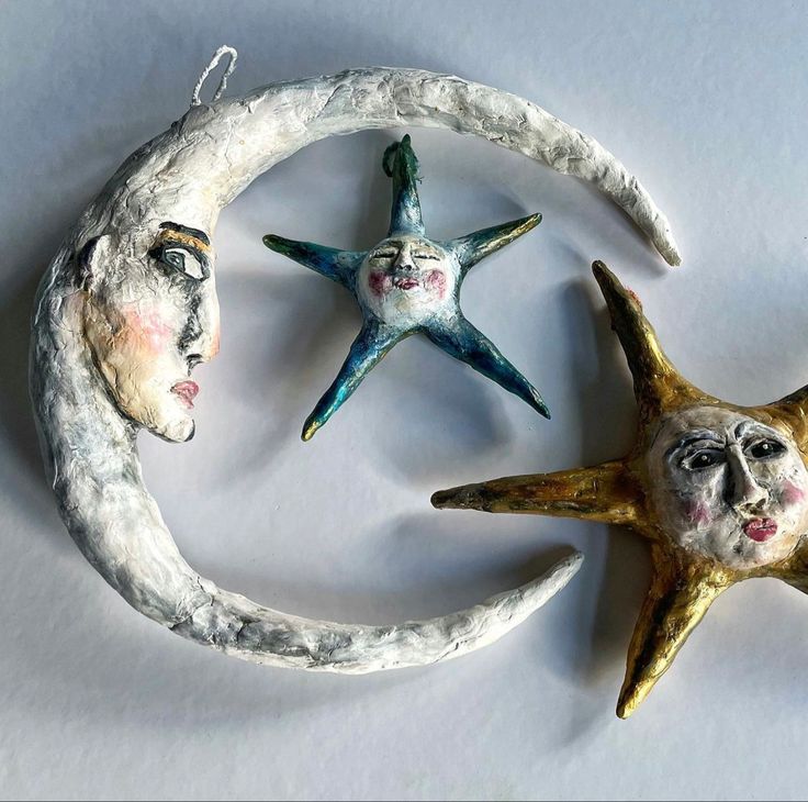 three ceramic moon and star ornaments on a white surface