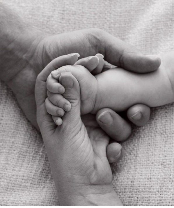 a black and white photo of a baby's feet being held by a parent