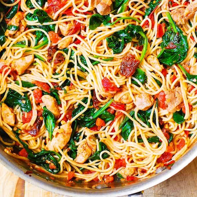 a pan filled with pasta and vegetables on top of a wooden table