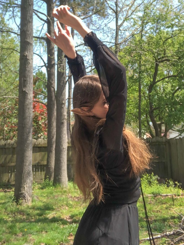 a woman standing in the grass holding her hands up