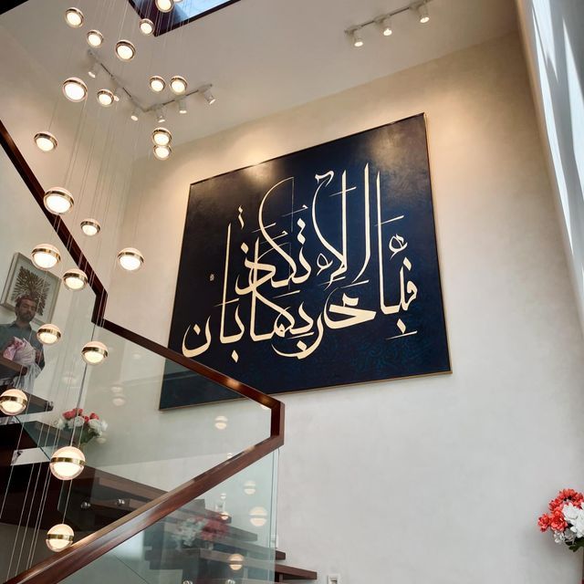 a large sign hanging on the side of a wall next to a stair case in a building