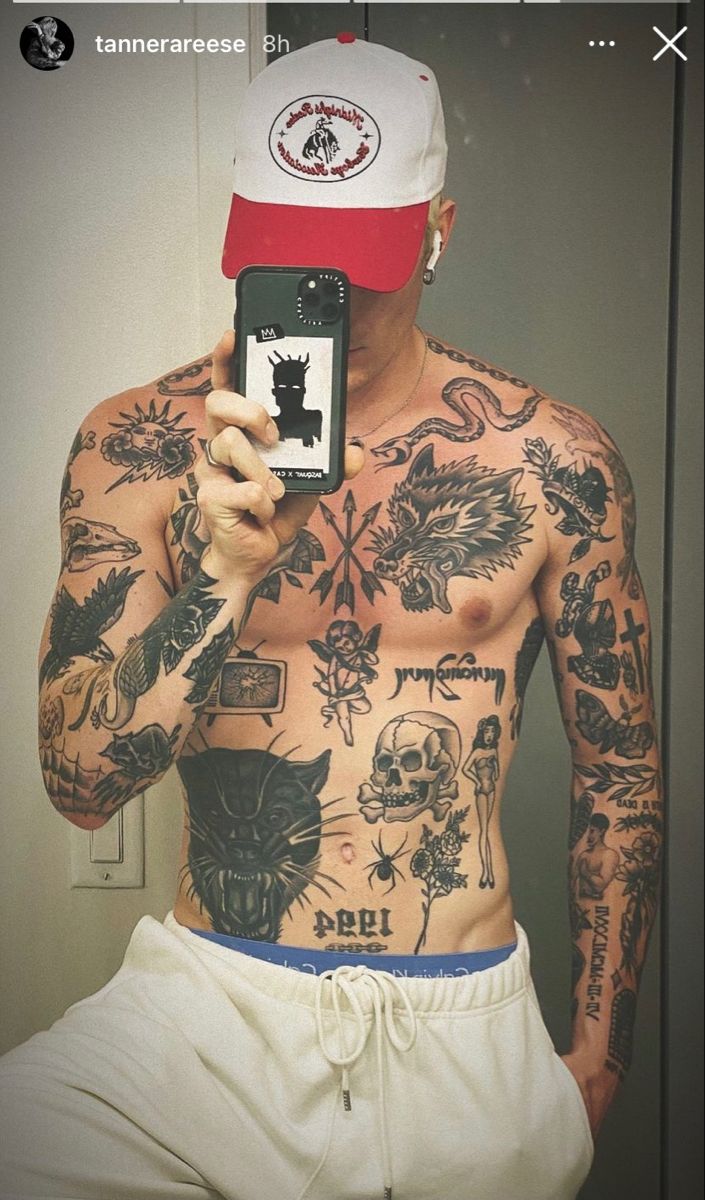 a man with tattoos taking a selfie in front of a mirror holding a cell phone