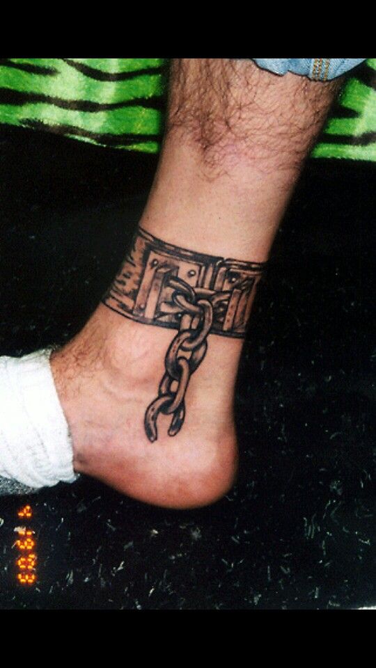 a man's foot with a tattoo on the ankle that has a chain attached to it