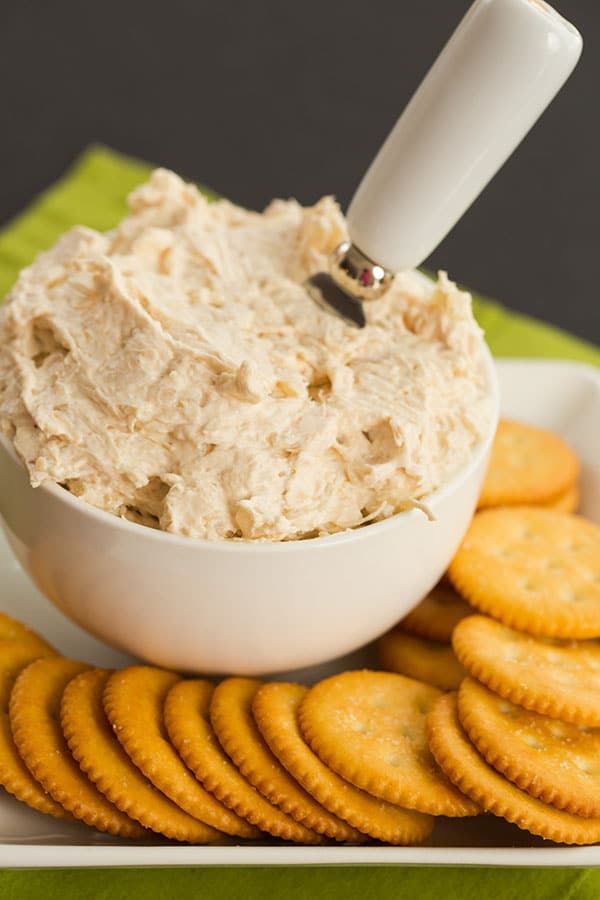 a white bowl filled with cream cheese surrounded by crackers