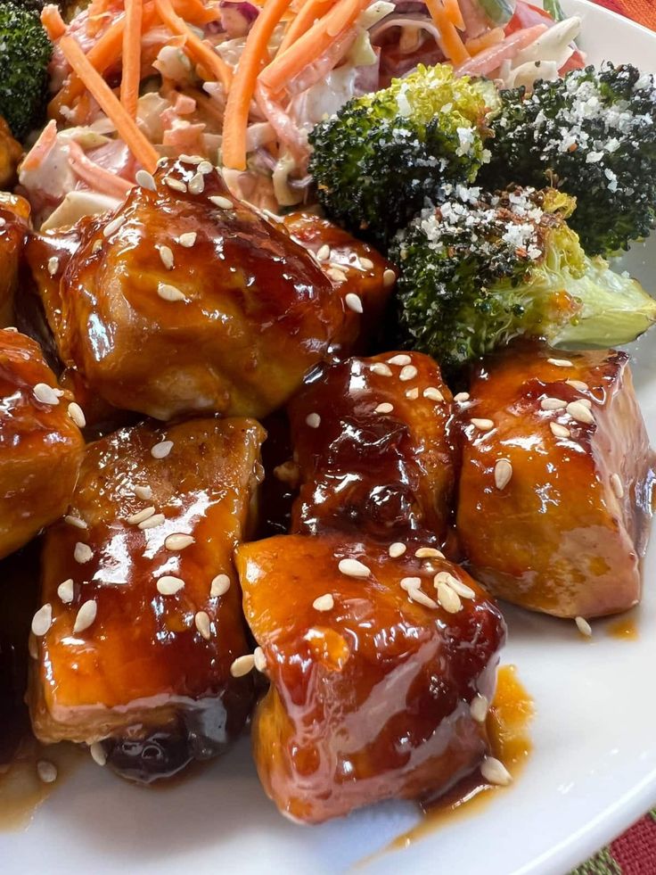 a white plate topped with chicken and broccoli covered in sesame seeds