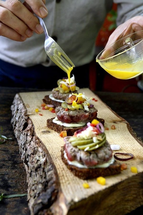 a person is pouring something into some food on a wooden cutting board with other foods