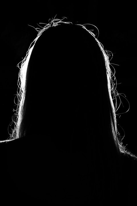 a woman with long hair standing in the dark