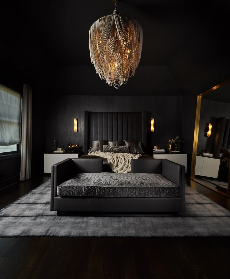 a black bedroom with a bed, mirror and chandelier