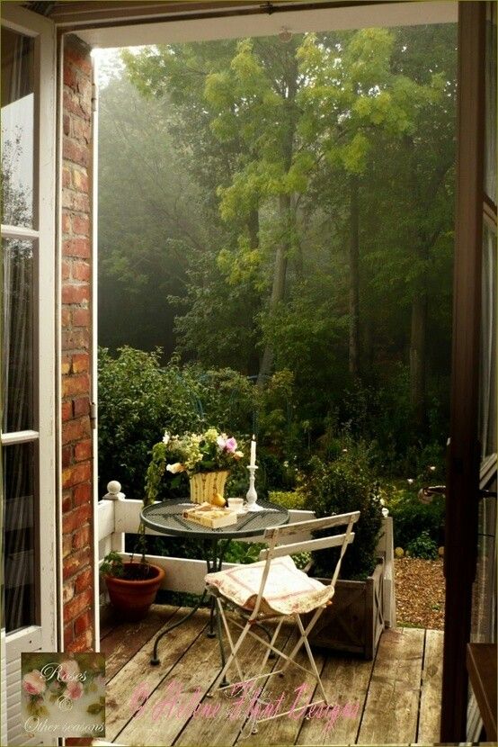 an outdoor table and chairs on a wooden deck in front of a door that leads out to a wooded area