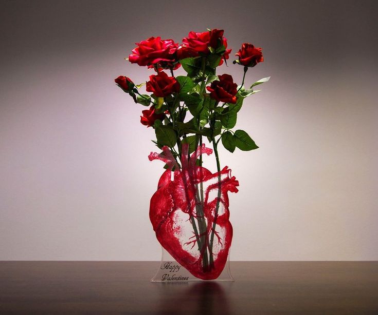 a vase filled with red roses on top of a wooden table