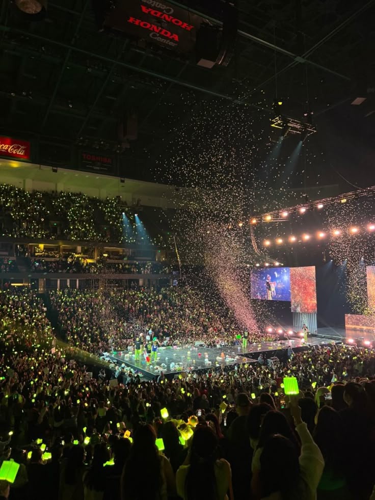 a large crowd at a concert with confetti in the air