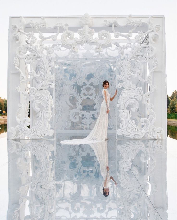 a woman in a white dress is reflected in the water on a clear day with her reflection