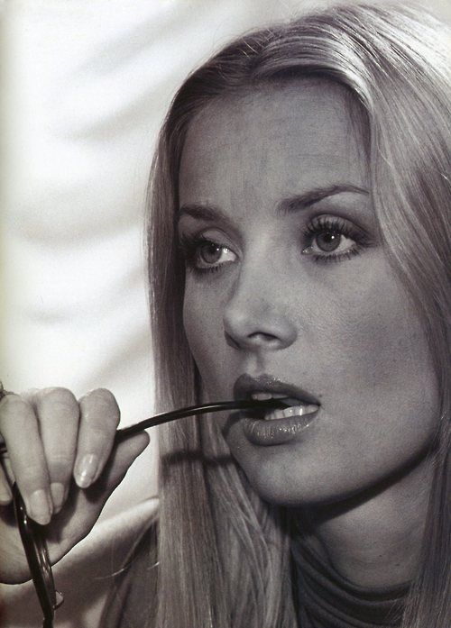 a woman with long hair is holding a spoon in her mouth and looking at the camera