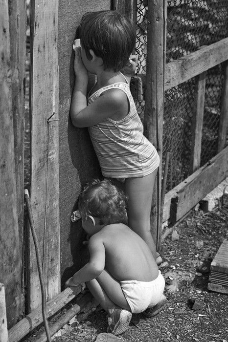 two children leaning against a wooden fence with the caption, allesta va lo veo