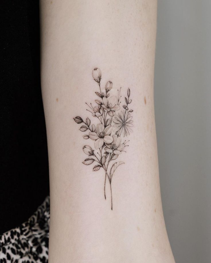 a small flower tattoo on the back of a woman's left arm and leg