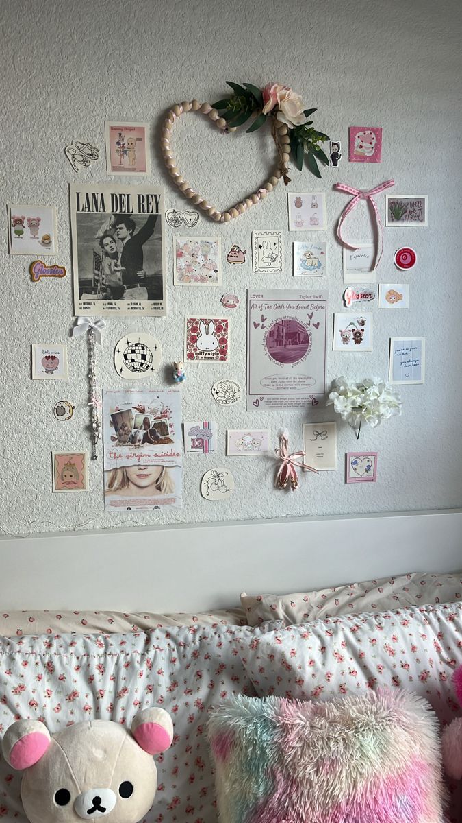 a teddy bear sitting on top of a bed next to a wall covered in pictures