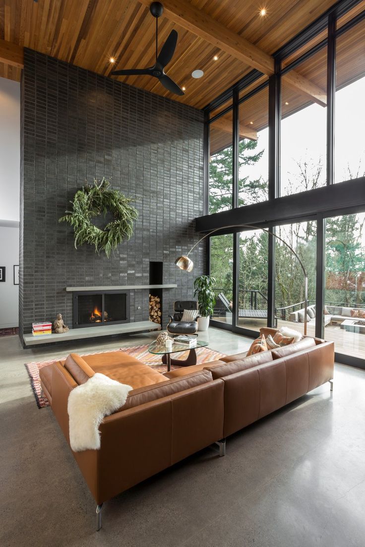 a living room with large windows and a couch in front of a fire place on the wall