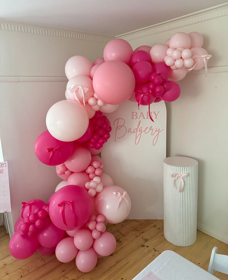 a balloon arch with pink and white balloons on the wall in a baby's room